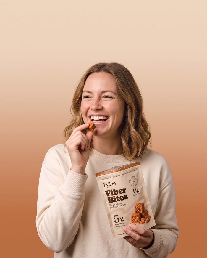 Laughing woman eating a Peanut Butter Fiber Bite