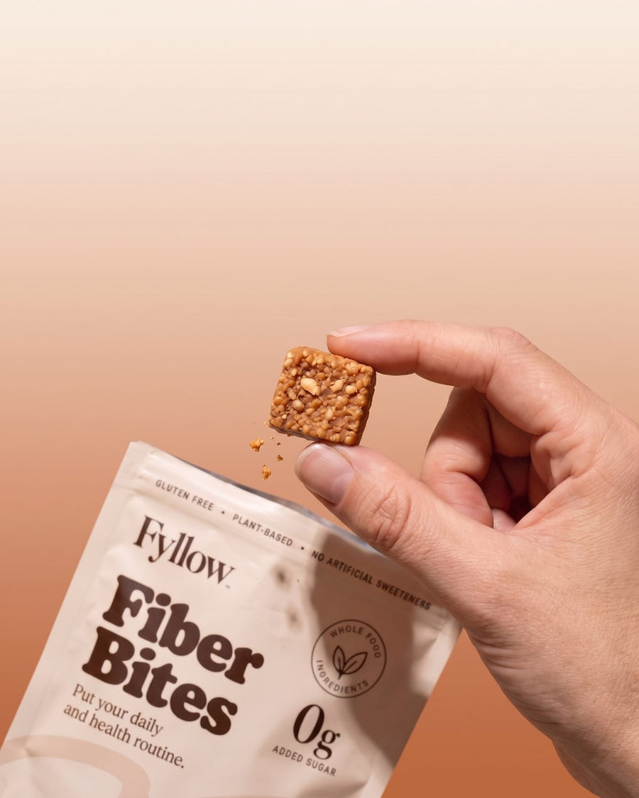 Hand holding a Peanut Butter Fiber Bite above the pouch